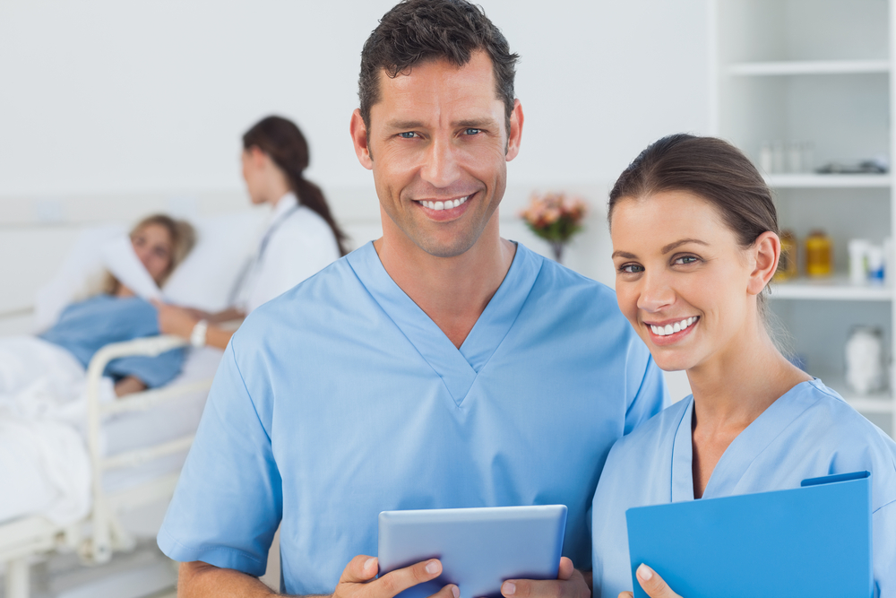 Portrait of surgeons in bright surgery with doctor attending patient on background